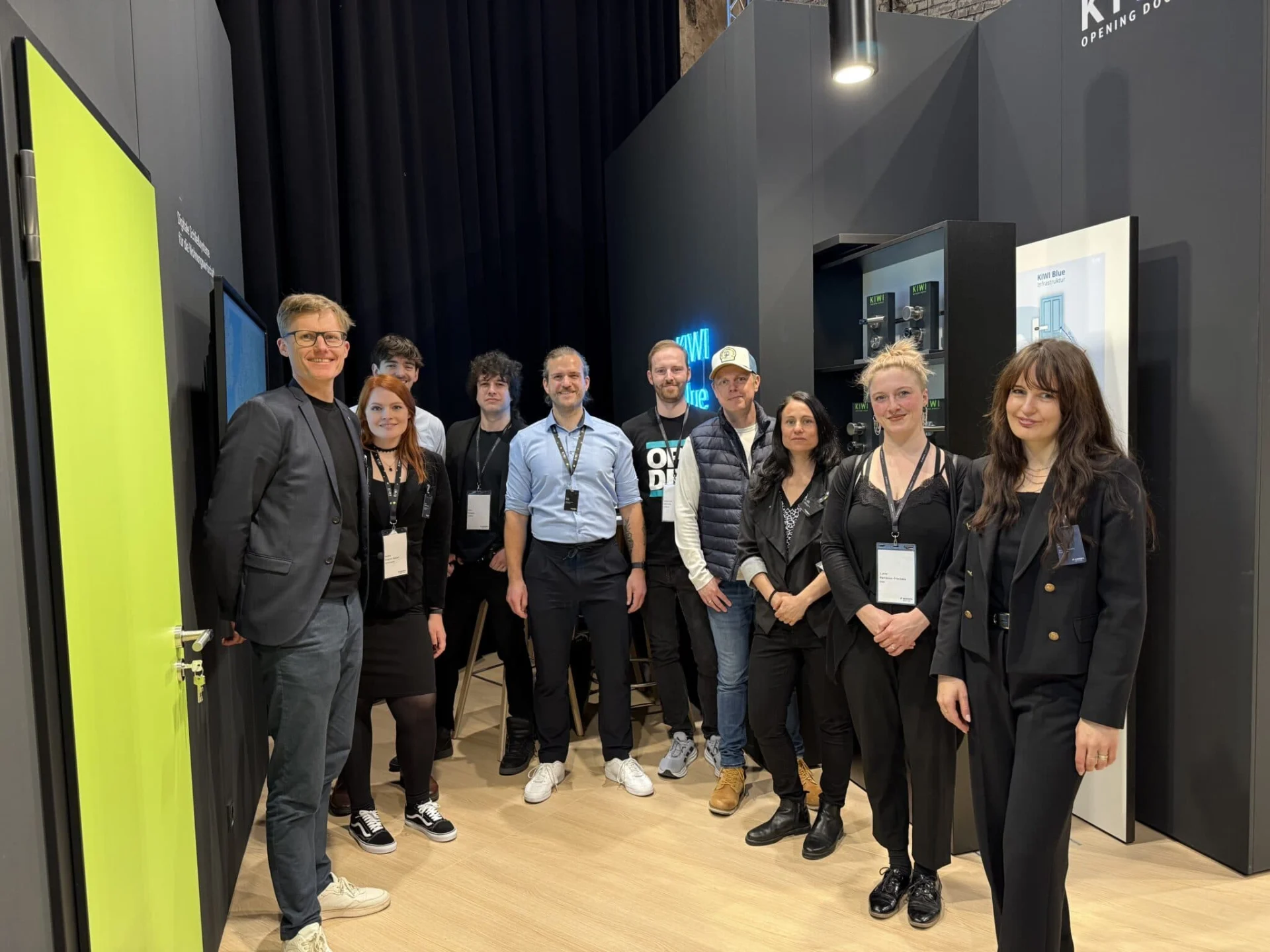 Team von KIWI beim Messeauftritt – das Team steht gemeinsam am Stand mit Produkten und Displays im Hintergrund und repräsentiert das Unternehmen professionell vor Ort.