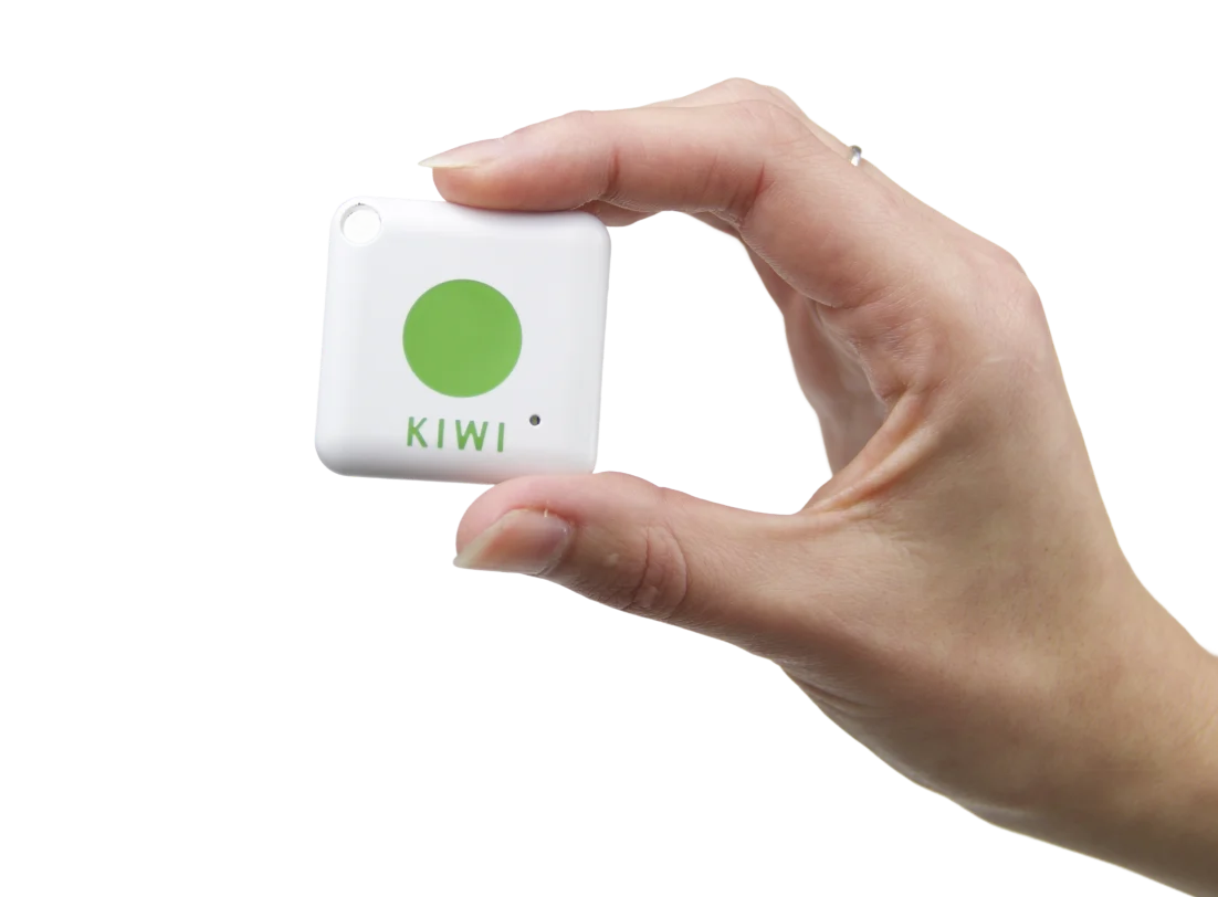 Hand hält einen weißen KIWI-Transponder mit grünem Punkt – kontaktloses Gerät für den digitalen Gebäudezutritt.