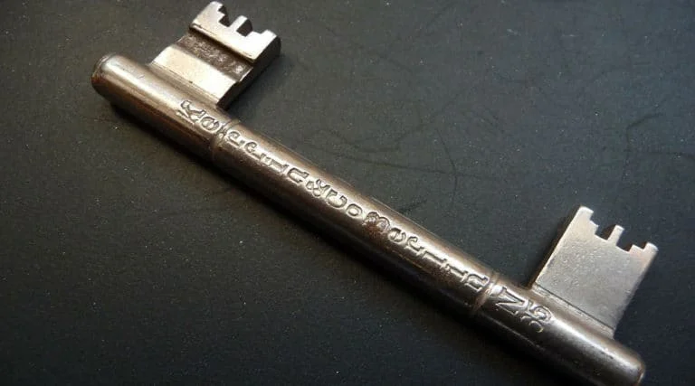 Ein rohrförmiger Metallschlüssel mit eingravierten Markierungen ruht auf einer dunklen Oberfläche.