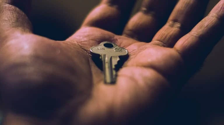 Nahaufnahme einer offenen Hand, die einen einzelnen Metallschlüssel hält.