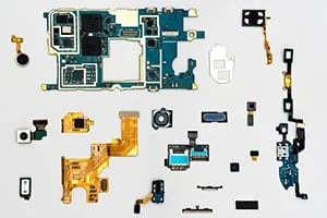 Verschiedene elektronische Bauteile und Leiterplatten eines zerlegten Geräts, angeordnet auf einem weißen Hintergrund.